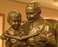 Statue of a man reading to boy on his lap