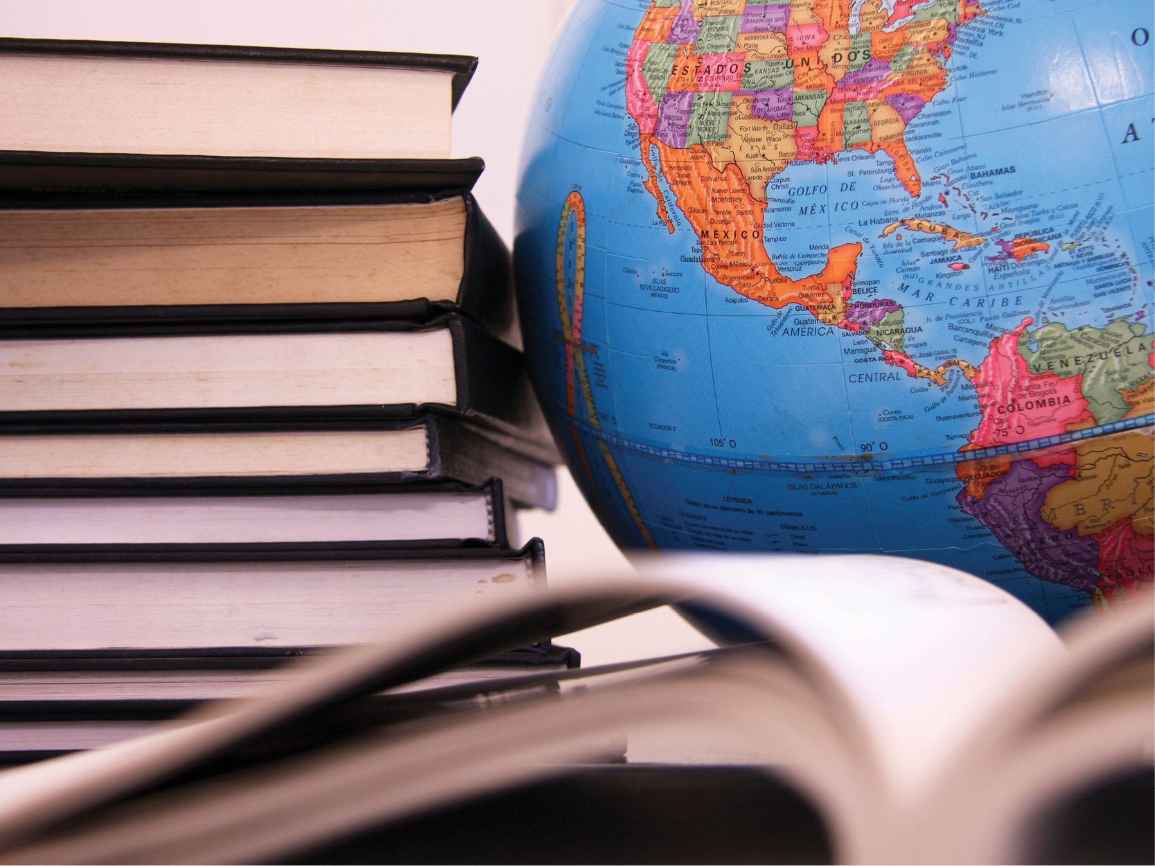 Open book and stack of books next to a globe