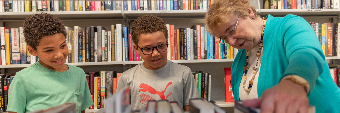 Book Seller volunteer and two kids looking at books