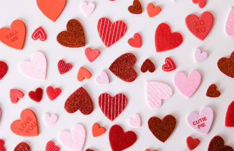 Many red and pink heart cutouts on a white surface