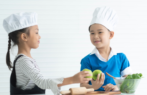 Two Kids wearing chefs hats holding apples