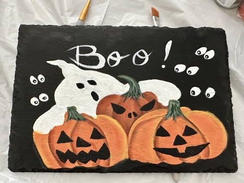 ghost behind jack-o'-lanterns painted on slate