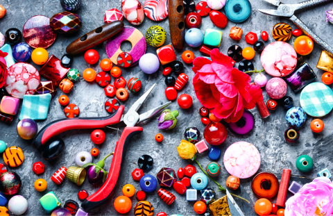 Multi-colored beads spread out with a pair of pliers and a rose