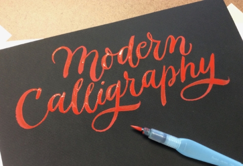 the word "Modern Calligraphy" written in orange on a black piece of paper