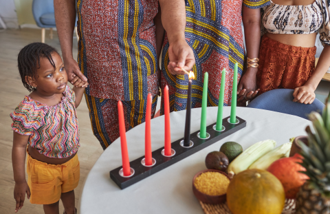 Black family observing Kwanzaa by lighting kinara