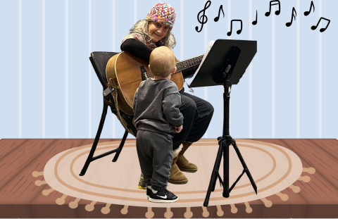 Silver hair lady wearing a knit cap sets playing the guitar while a toddler with back to us listens.