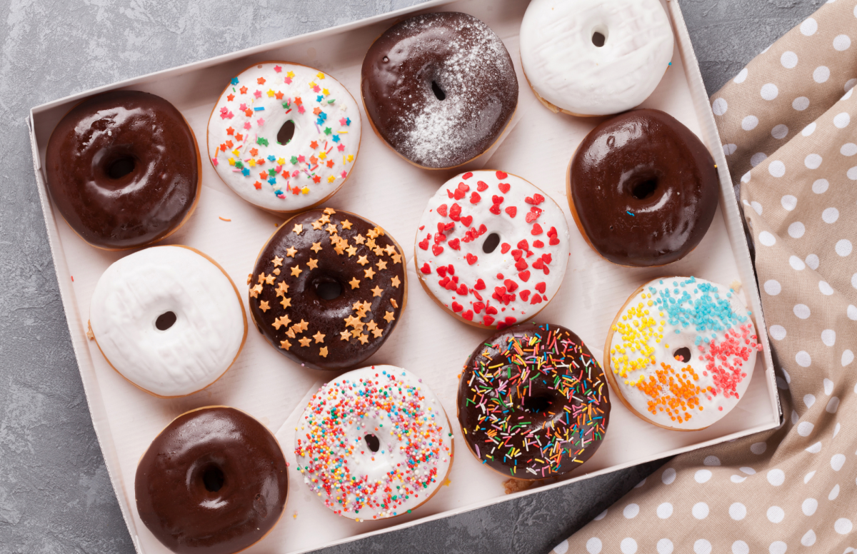 Baking tray holding a dozen differrently frosted donuts