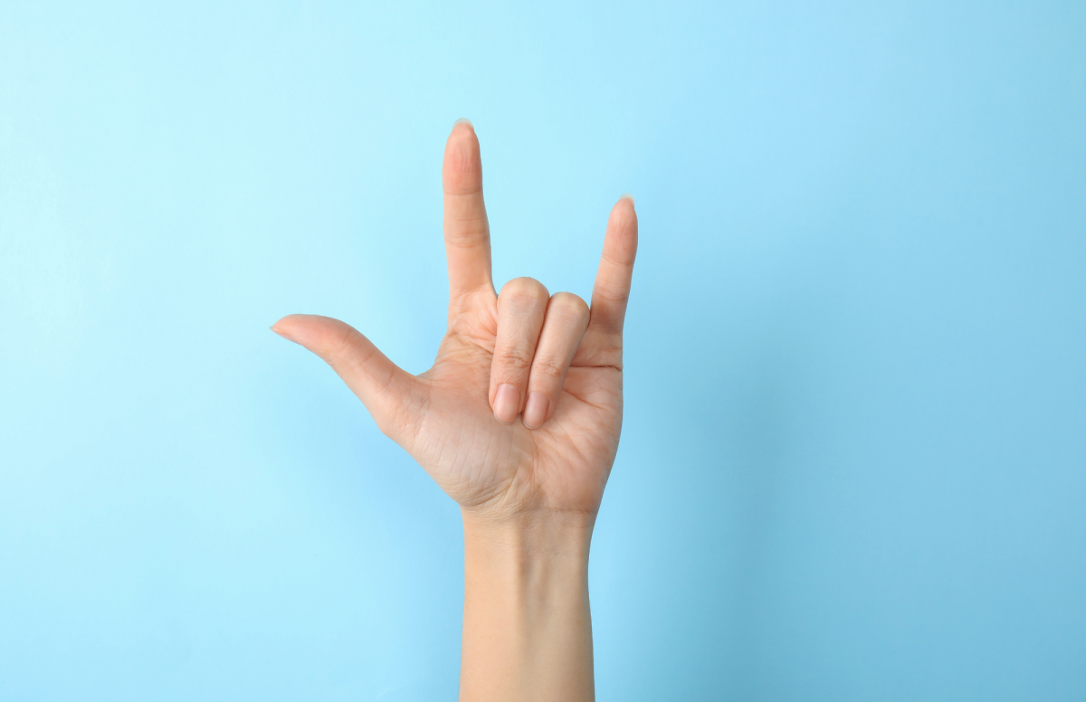 White hand signing I Love You in front of a blue background