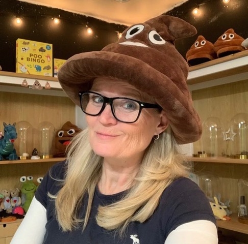 Blond whtie woman wearing a Poop stuffie hat