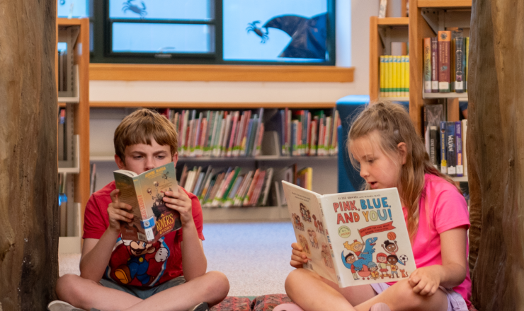 Boy and girl sitting in the children's area reading books